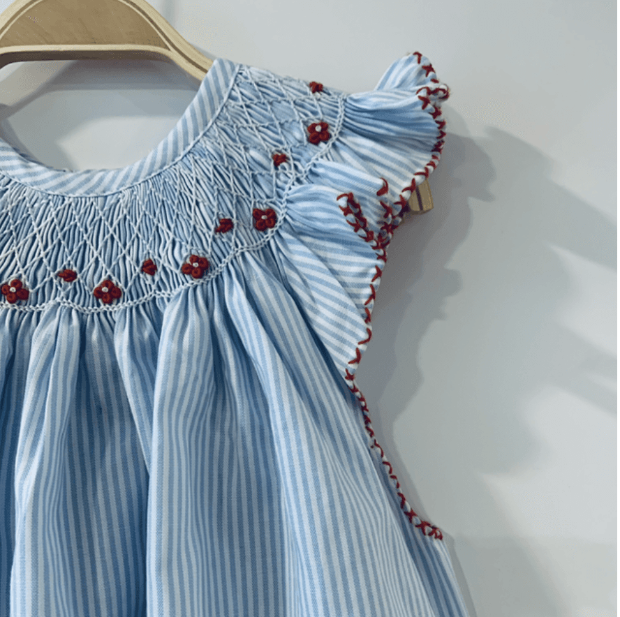 Blue and white striped dress with smocked neckline, red floral embroidery, and ruffled sleeves.